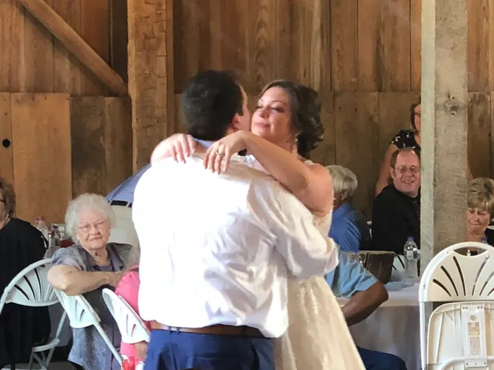 A bride dancing with a family member in a rustic venue