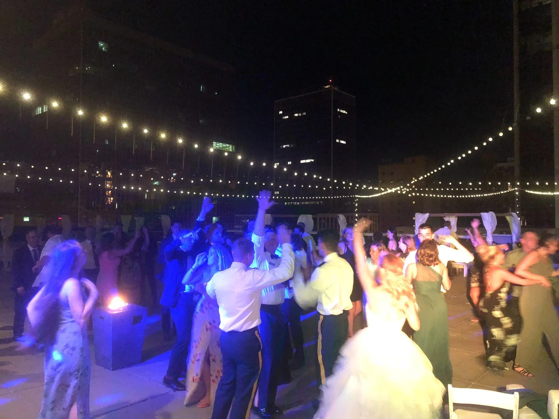 Wedding reception dancing on a rooftop beneath string lights